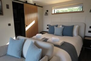 Double bed and seating Double bed with blue cushions and a sofa in an Angusfield cabin
