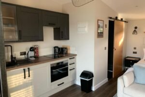 Cabin kitchen and living space Black kitchen cabinets and seating inside an Angusfield cabin